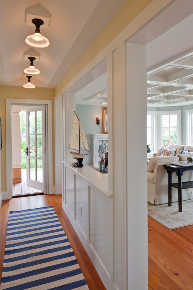 This is an example of a mid-sized beach style hallway in Boston with beige walls, medium hardwood floors and brown floor.