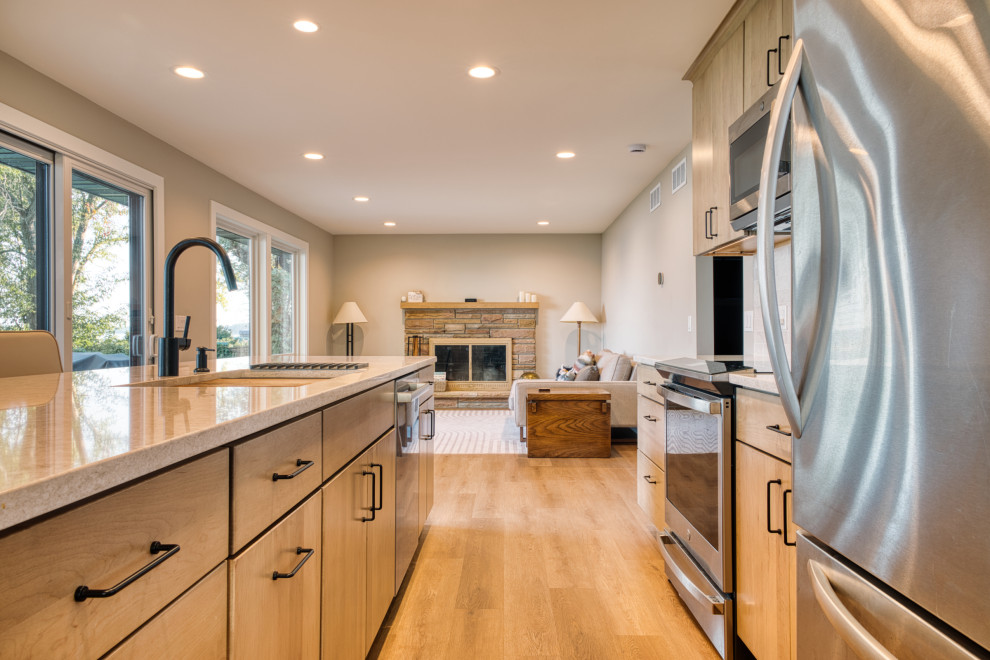 Mid-sized transitional galley vinyl floor and brown floor open concept kitchen photo with an undermount sink, flat-panel cabinets, light wood cabinets, quartz countertops, white backsplash, subway tile backsplash, stainless steel appliances, an island and white countertops