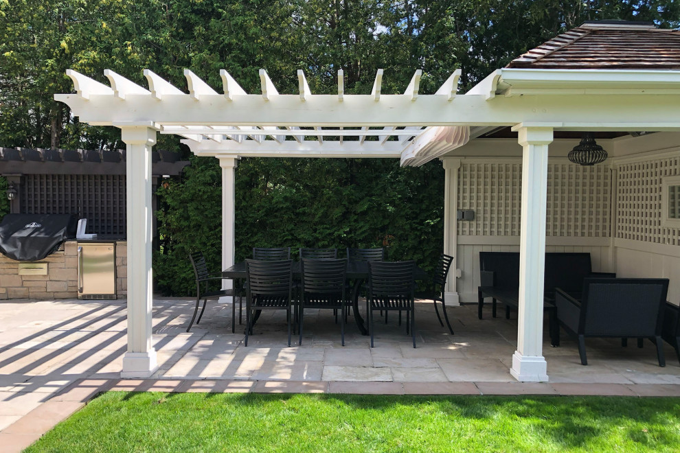 This is an example of a large classic back patio in Toronto with concrete paving and a pergola.