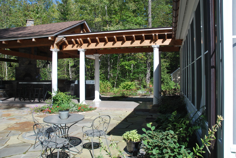 Photo of a traditional backyard patio in Portland Maine with an outdoor kitchen, natural stone pavers and a roof extension.