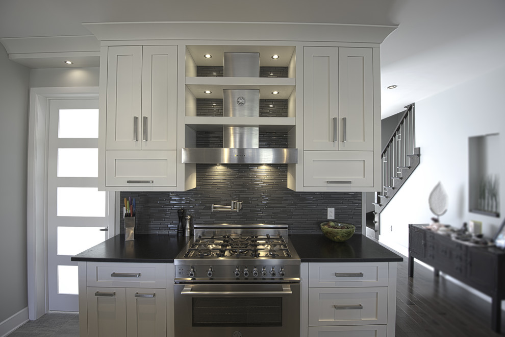 Design ideas for a large transitional u-shaped separate kitchen in Montreal with an undermount sink, shaker cabinets, white cabinets, quartzite benchtops, grey splashback, matchstick tile splashback, stainless steel appliances, vinyl floors, with island, brown floor and black benchtop.