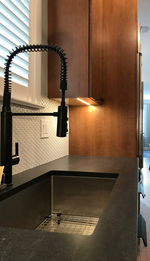 This is an example of a large midcentury l-shaped eat-in kitchen in Chicago with an undermount sink, flat-panel cabinets, brown cabinets, quartz benchtops, white splashback, ceramic splashback, stainless steel appliances, medium hardwood floors, with island, brown floor and black benchtop.