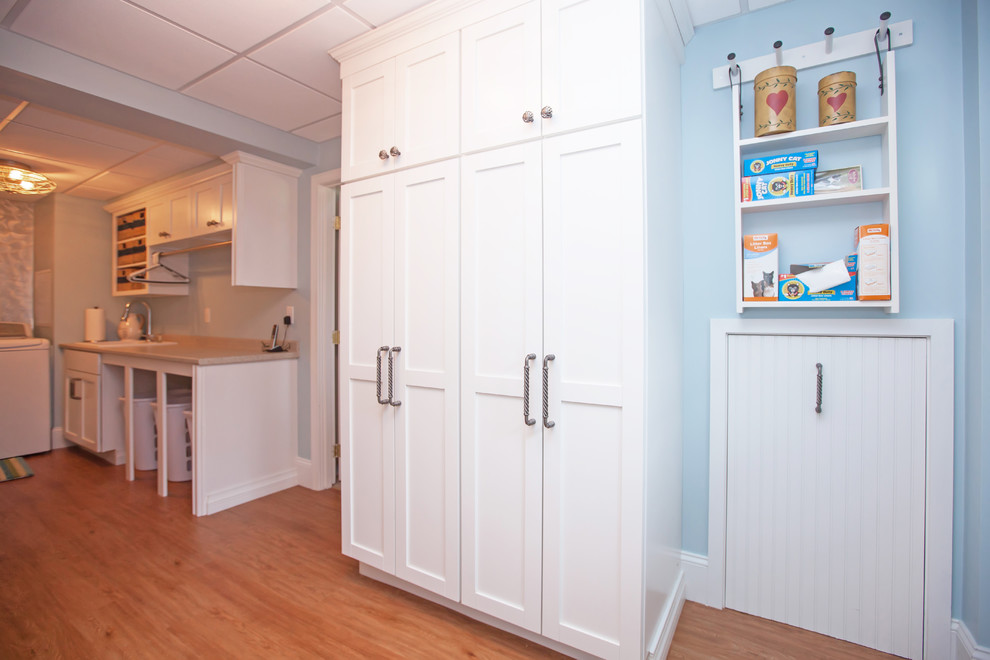 Mid-sized beach style galley dedicated laundry room in Boston with a single-bowl sink, shaker cabinets, white cabinets, laminate benchtops, blue walls, linoleum floors and a side-by-side washer and dryer.