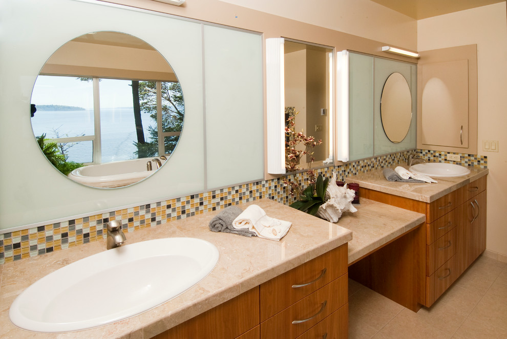 Photo of a transitional bathroom in Seattle with a drop-in sink, flat-panel cabinets, medium wood cabinets, granite benchtops, a drop-in tub, beige tile, stone tile, white walls and ceramic floors.