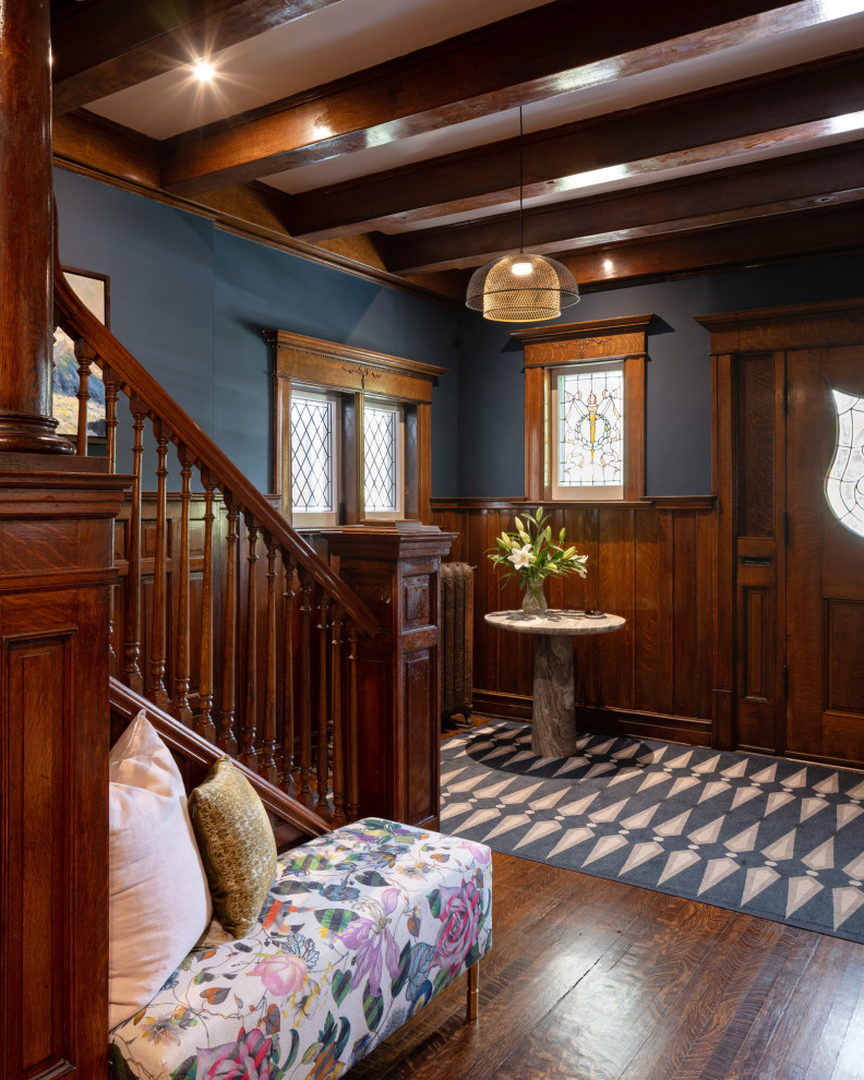 Großes Klassisches Foyer mit blauer Wandfarbe, dunklem Holzboden, Einzeltür, hellbrauner Holzhaustür, freigelegten Dachbalken und vertäfelten Wänden in Toronto