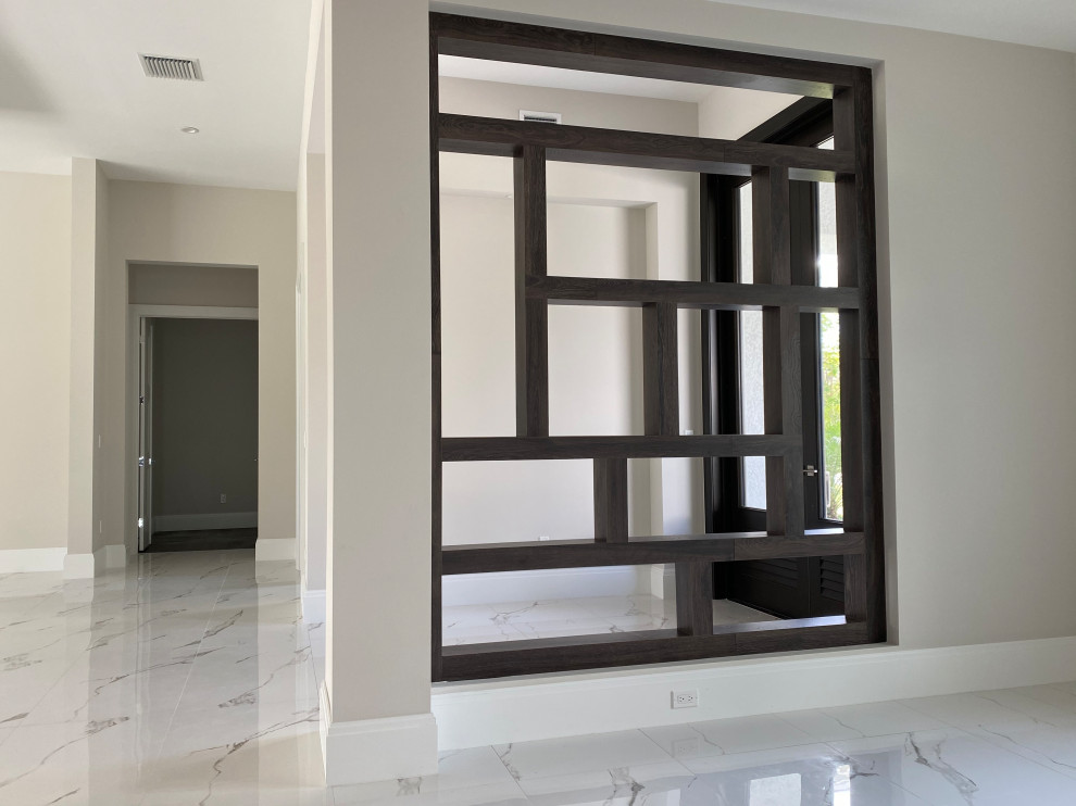 Small transitional porcelain tile and white floor foyer photo in Miami with beige walls and a black front door
