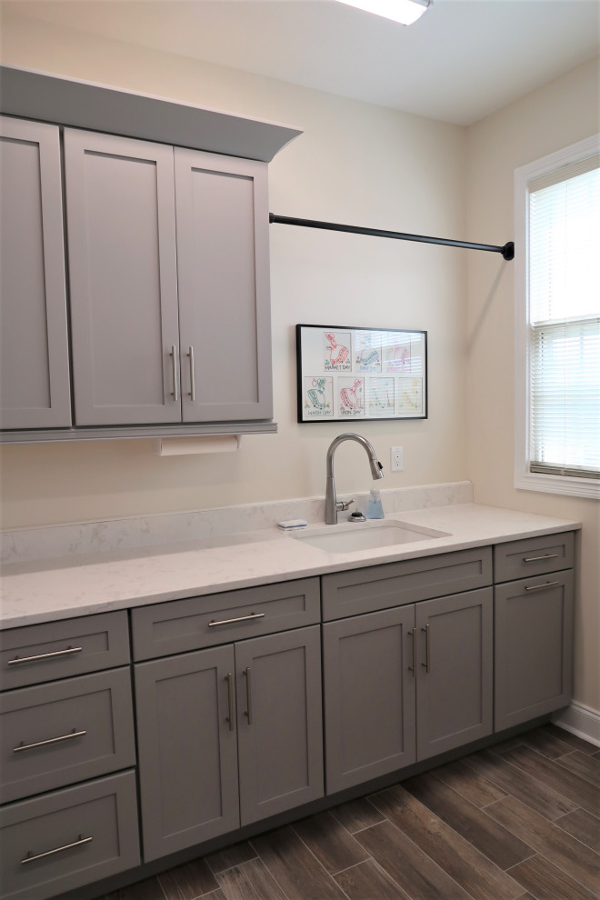 Dedicated laundry room - mid-sized modern single-wall dark wood floor and brown floor dedicated laundry room idea in Other with an undermount sink, shaker cabinets, gray cabinets, quartzite countertops, beige walls and white countertops