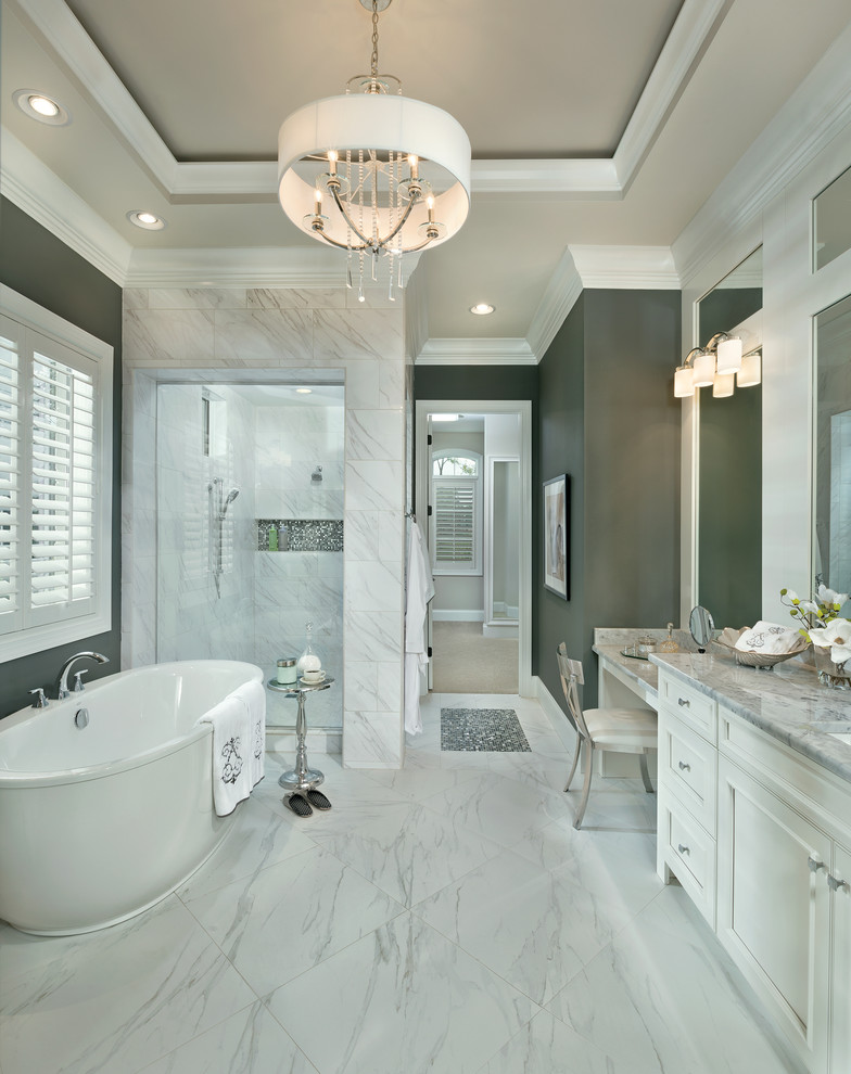 This is an example of a large transitional master bathroom in Cincinnati with an undermount sink, recessed-panel cabinets, white cabinets, marble benchtops, a freestanding tub, an alcove shower, white tile, grey walls, porcelain tile, porcelain floors and white floor.