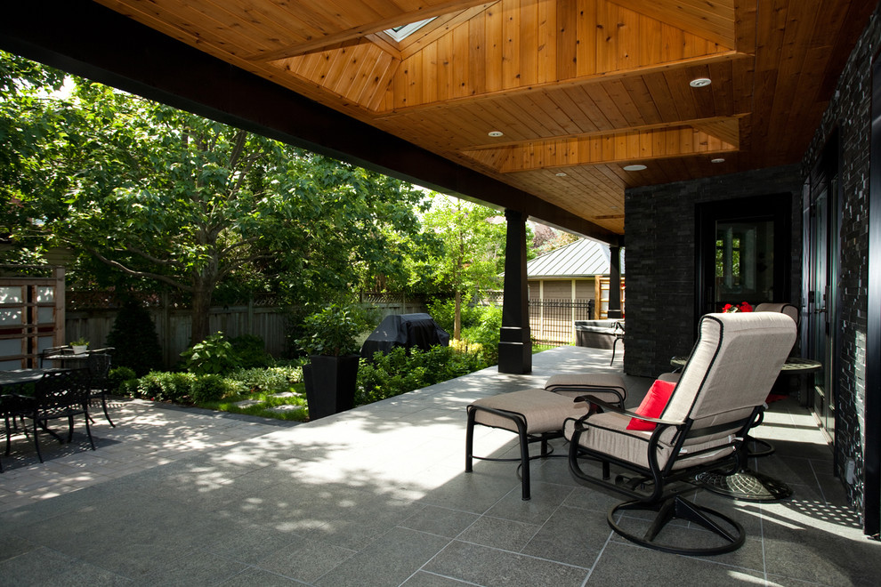 Photo of a mid-sized contemporary backyard patio in Ottawa with tile and a roof extension.