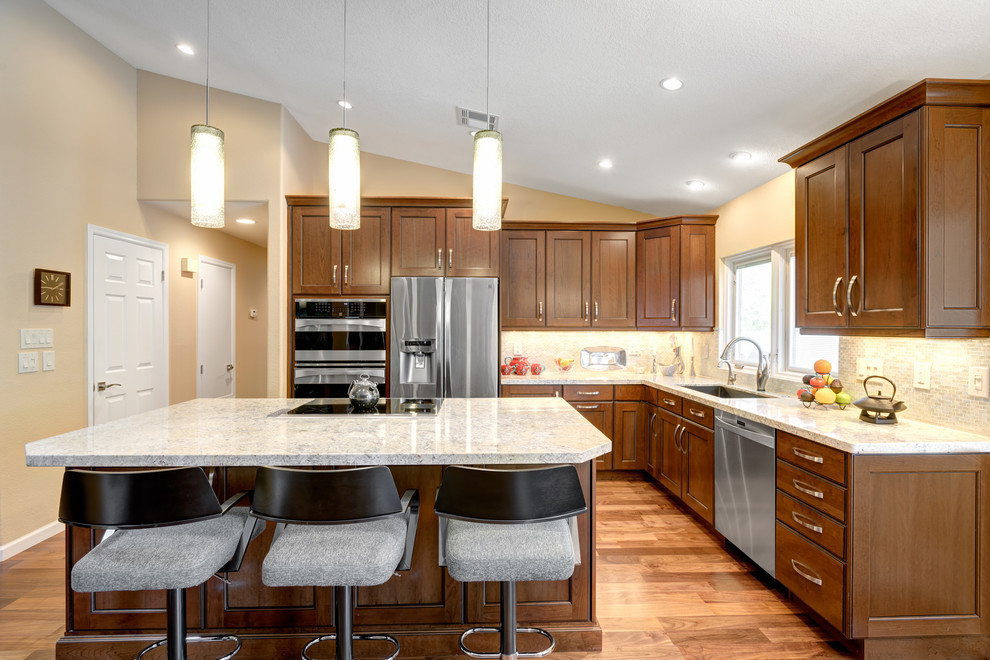 Large transitional l-shaped light wood floor eat-in kitchen photo in Phoenix with flat-panel cabinets, medium tone wood cabinets, quartz countertops, beige backsplash, glass tile backsplash, stainless steel appliances, an island and an undermount sink