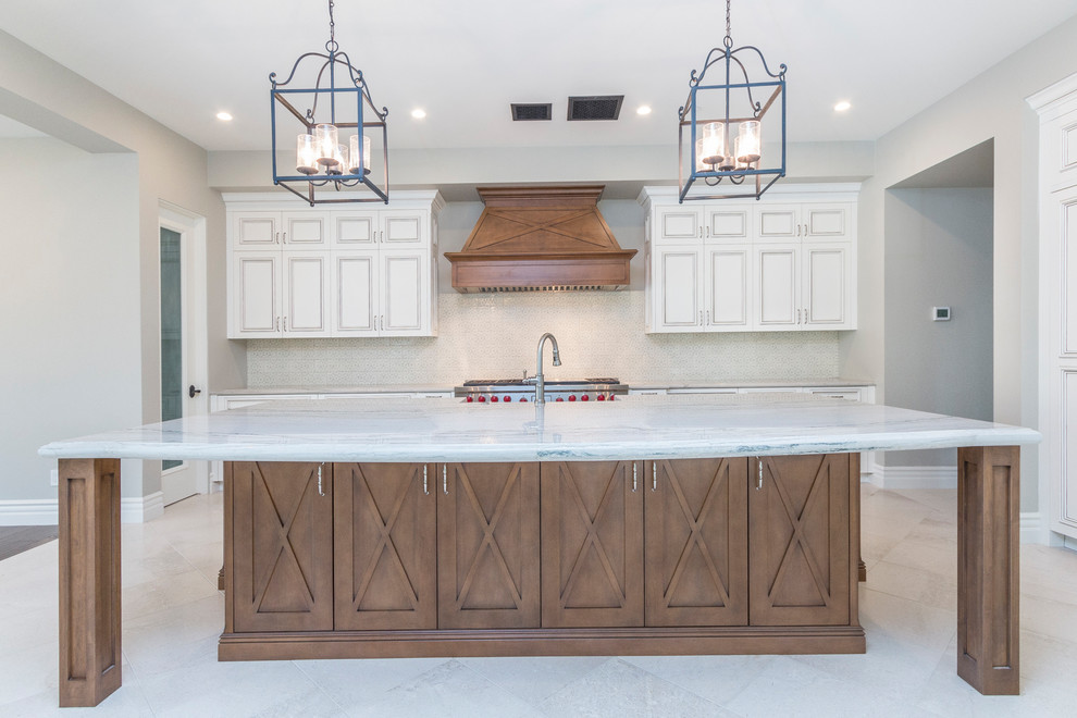 Example of a huge transitional l-shaped limestone floor and beige floor open concept kitchen design in Phoenix with a farmhouse sink, raised-panel cabinets, white cabinets, quartzite countertops, white backsplash, stone tile backsplash, paneled appliances and an island
