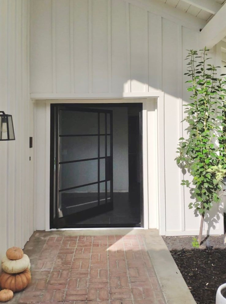Photo of a mid-sized contemporary front door in Orange County with white walls, brick floors, a pivot front door, a black front door and red floor.