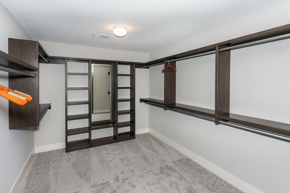 Design ideas for a large arts and crafts gender-neutral walk-in wardrobe in Wichita with dark wood cabinets and carpet.