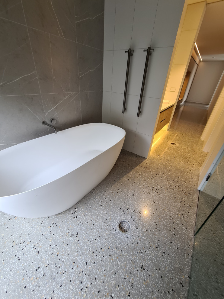 Medium sized contemporary bathroom in Melbourne with flat-panel cabinets, light wood cabinets, a freestanding bath, black and white tiles, metro tiles, concrete flooring, quartz worktops, grey floors, white worktops, a single sink and a floating vanity unit.