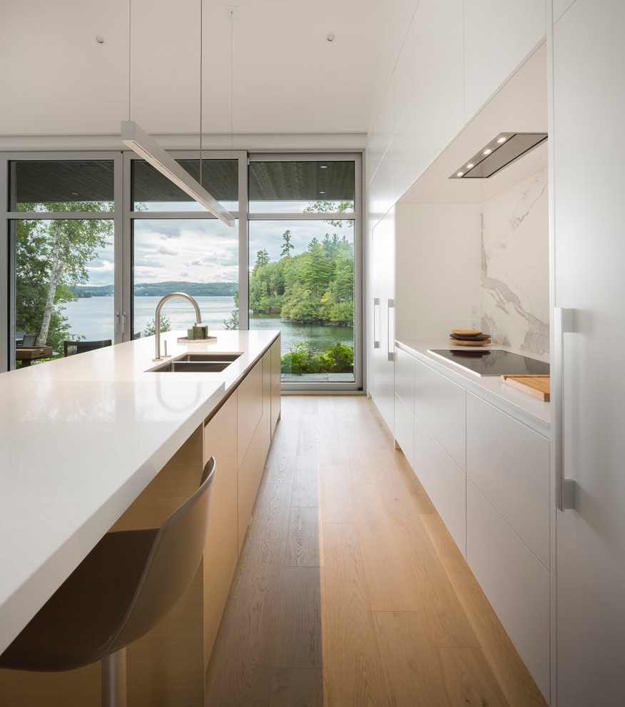 Design ideas for a small contemporary galley eat-in kitchen in Sydney with a double-bowl sink, flat-panel cabinets, white cabinets, quartz benchtops, porcelain splashback, coloured appliances, light hardwood floors, with island and white benchtop.