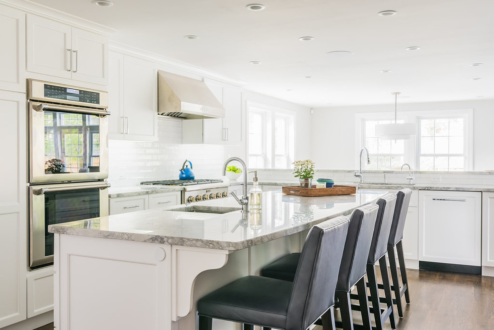 Inspiration for a mid-sized traditional u-shaped open plan kitchen in Boston with shaker cabinets, white cabinets, white splashback, stainless steel appliances, dark hardwood floors, with island, an undermount sink, subway tile splashback, brown floor, grey benchtop and marble benchtops.