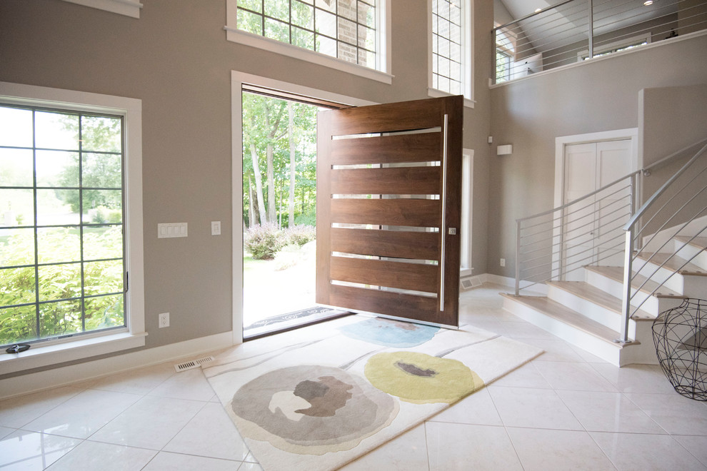 This is an example of a transitional entryway in Milwaukee with grey walls, a pivot front door, a dark wood front door and white floor.