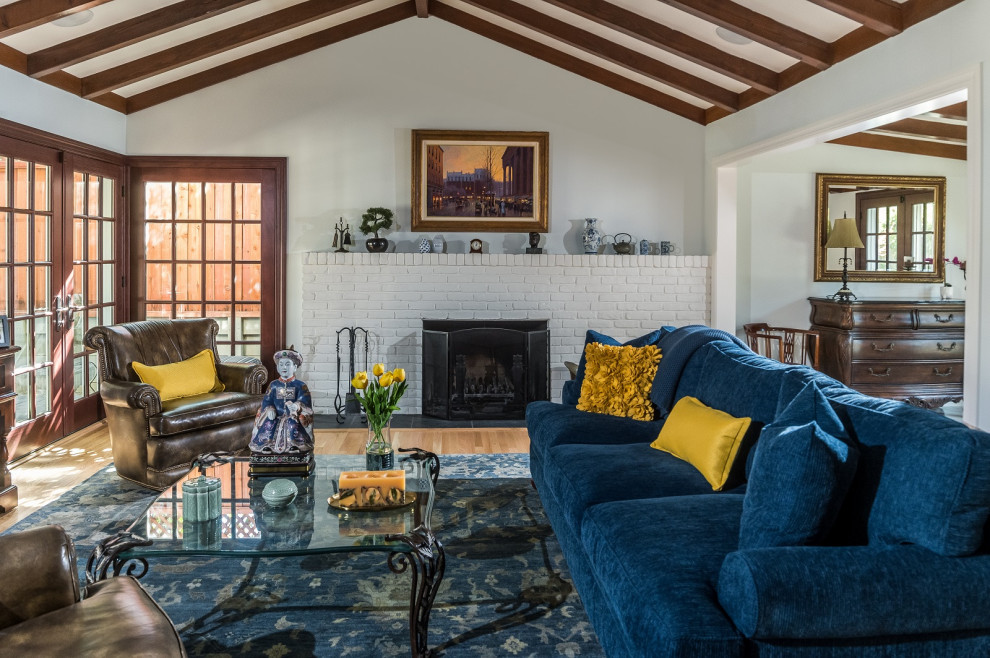 This is an example of a large traditional formal enclosed living room in San Francisco with blue walls, medium hardwood flooring, a standard fireplace, a brick fireplace surround, brown floors and exposed beams.