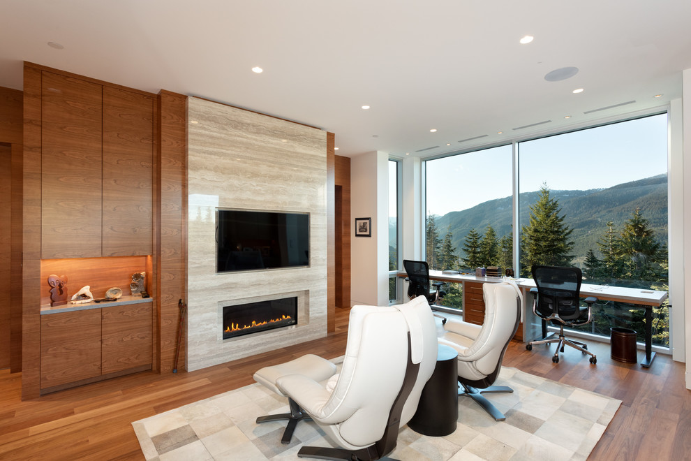 Large contemporary home studio in Vancouver with light hardwood floors, a ribbon fireplace, a stone fireplace surround, a freestanding desk and brown floor.