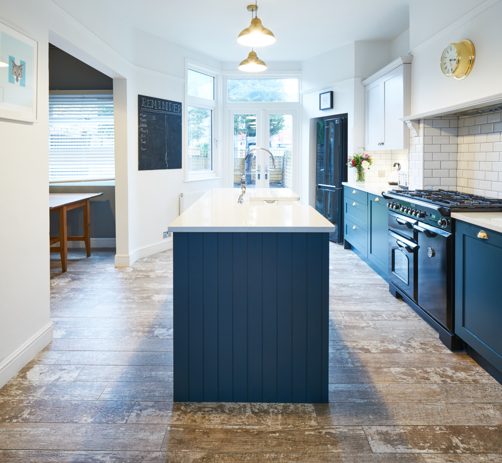 Design ideas for a contemporary eat-in kitchen in London with a farmhouse sink, shaker cabinets, blue cabinets, solid surface benchtops, white splashback, subway tile splashback, panelled appliances, medium hardwood floors and with island.