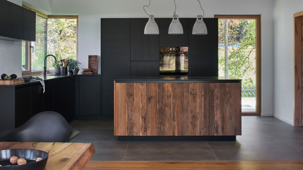 Стильный дизайн: кухня-гостиная в стиле модернизм с гранитной столешницей, островом и черным полом - последний тренд