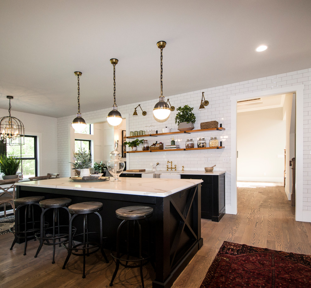 Design ideas for a large country galley eat-in kitchen in St Louis with shaker cabinets, quartz benchtops, white splashback, subway tile splashback, stainless steel appliances, medium hardwood floors, with island, brown floor, white benchtop, an undermount sink and black cabinets.