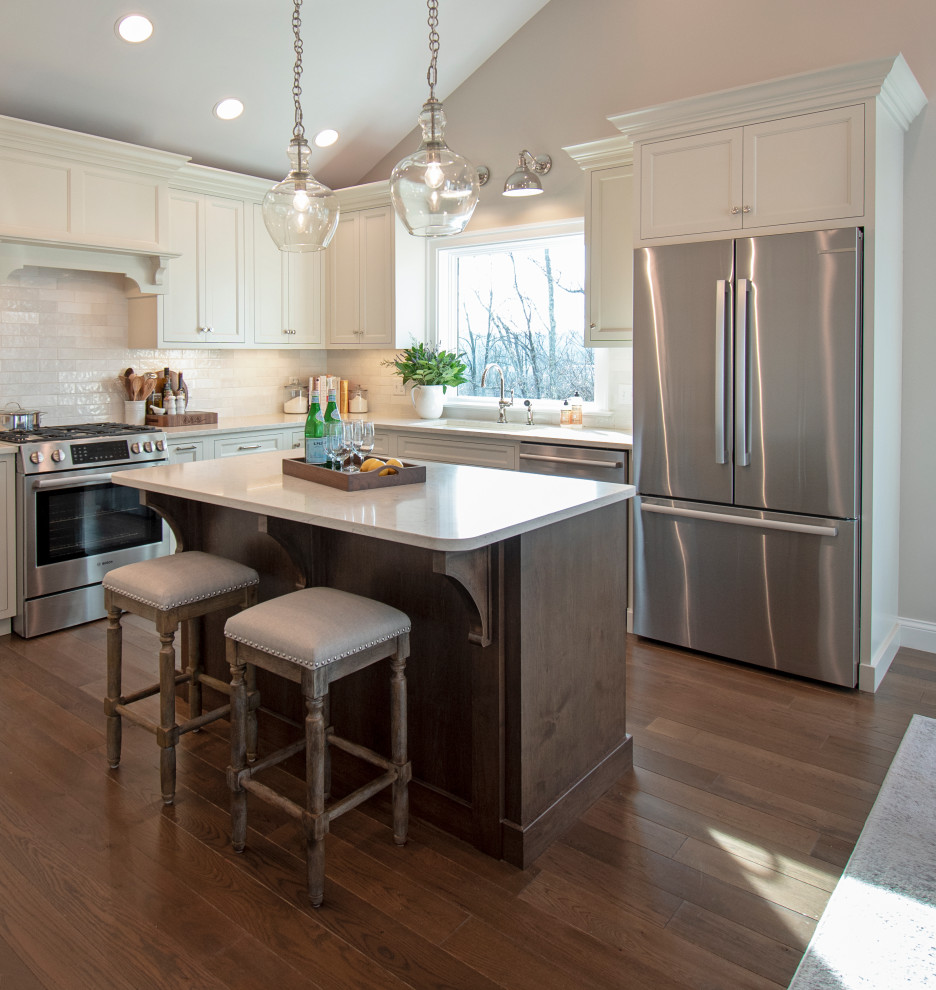 Eat-in kitchen - transitional medium tone wood floor, brown floor and vaulted ceiling eat-in kitchen idea with an undermount sink, shaker cabinets, white cabinets, quartz countertops, white backsplash, ceramic backsplash, stainless steel appliances, an island and white countertops