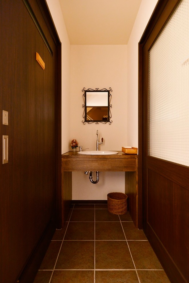 Photo of a mediterranean powder room in Tokyo with white walls and brown floor.