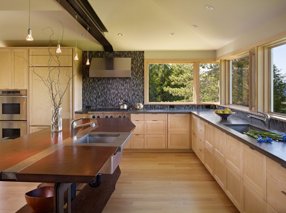 This is an example of a mid-sized contemporary l-shaped eat-in kitchen in Seattle with shaker cabinets, light wood cabinets, with island, an undermount sink, limestone benchtops, panelled appliances and light hardwood floors.