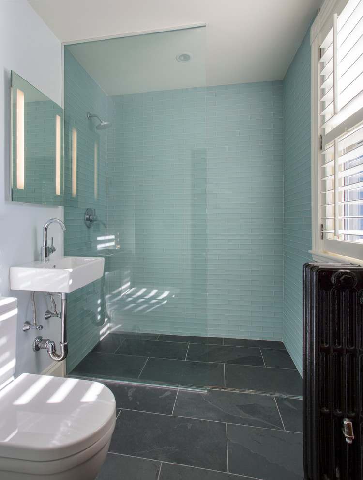 Photo of a small transitional master bathroom in Boston with a wall-mount sink, a curbless shower, a wall-mount toilet, blue tile, glass tile, white walls and slate floors.