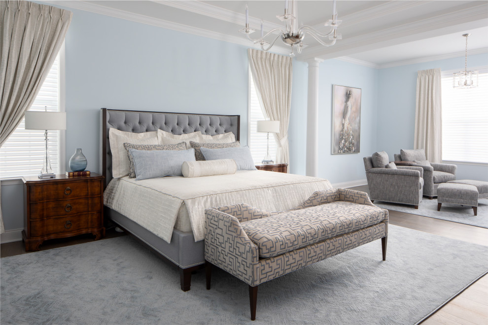 Aménagement d'une très grande chambre parentale beige et blanche classique avec un mur bleu, un sol en bois brun, un sol marron et un plafond décaissé.