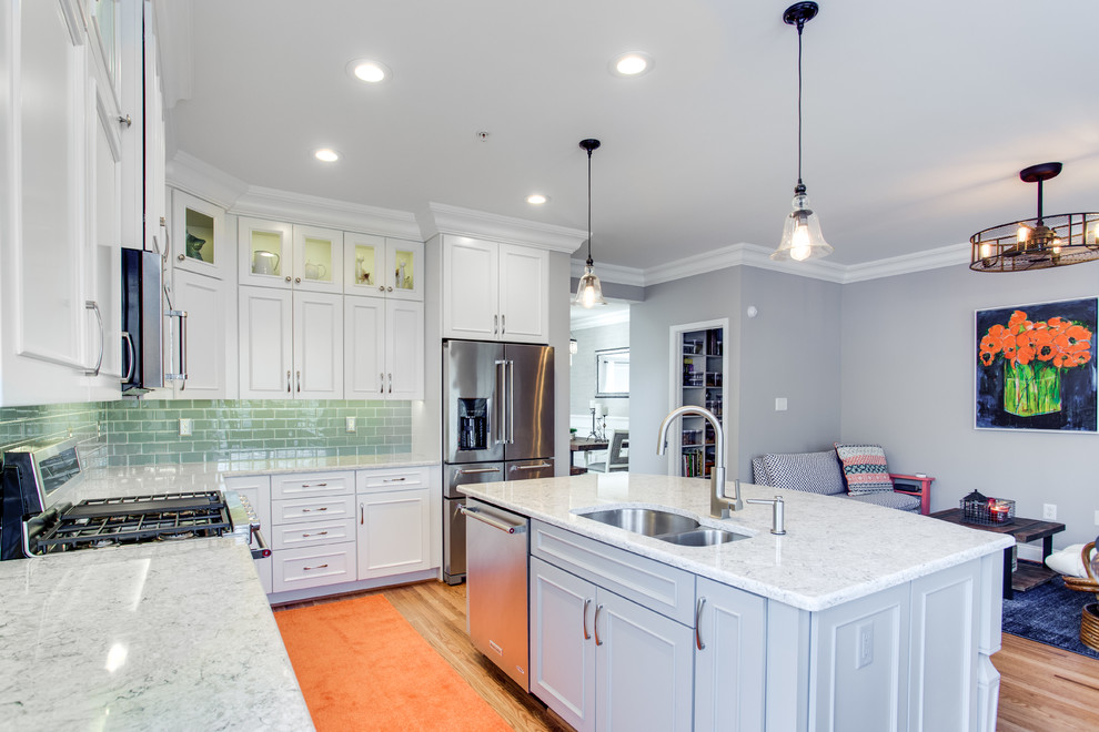 Inspiration for a mid-sized transitional l-shaped medium tone wood floor kitchen remodel in Baltimore with an undermount sink, recessed-panel cabinets, white cabinets, quartz countertops, green backsplash, subway tile backsplash, stainless steel appliances and an island