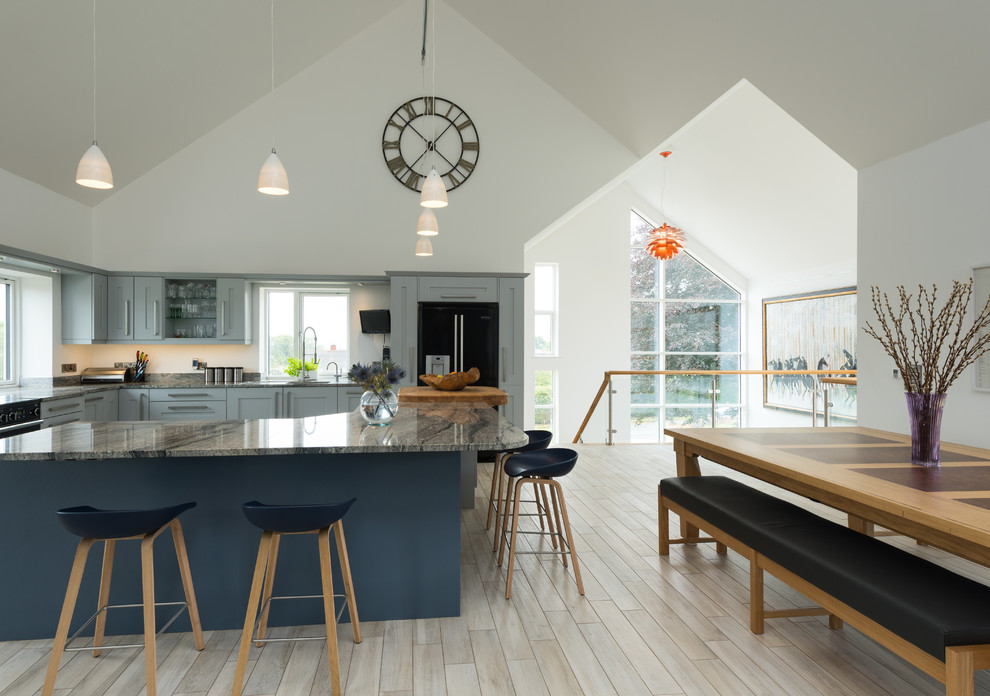 Design ideas for a large contemporary l-shaped eat-in kitchen in West Midlands with recessed-panel cabinets, blue cabinets, black appliances, light hardwood floors, with island, an undermount sink and marble benchtops.