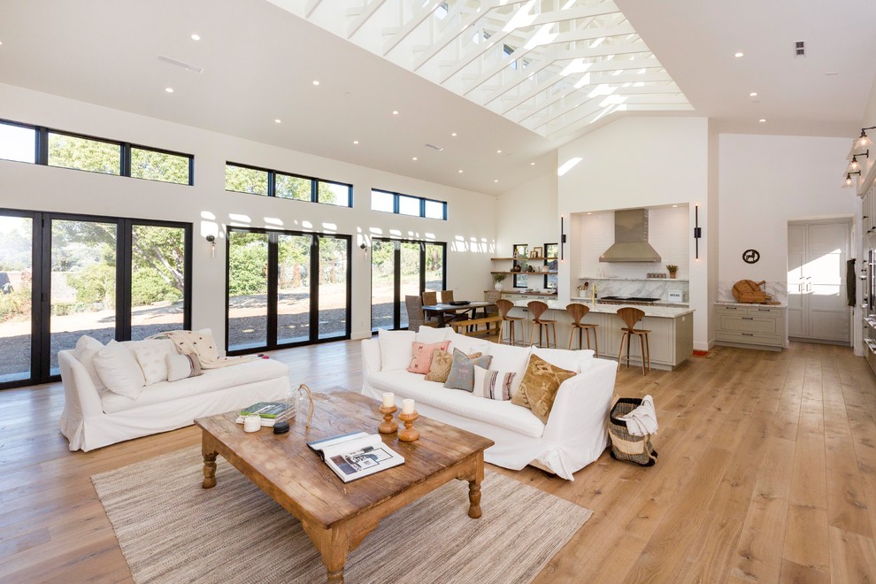 Expansive country open concept living room in San Diego with white walls, medium hardwood floors and brown floor.