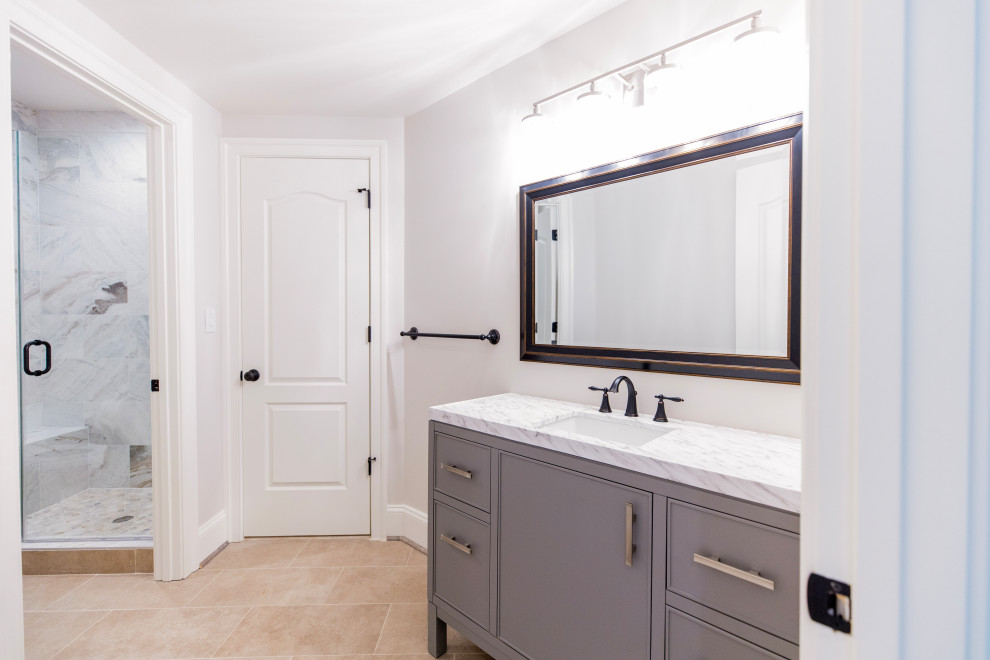 Modern inredning av ett litet vit vitt badrum med dusch, med möbel-liknande, grå skåp, ett hörnbadkar, en hörndusch, vit kakel, vita väggar, marmorbänkskiva, beiget golv och dusch med skjutdörr