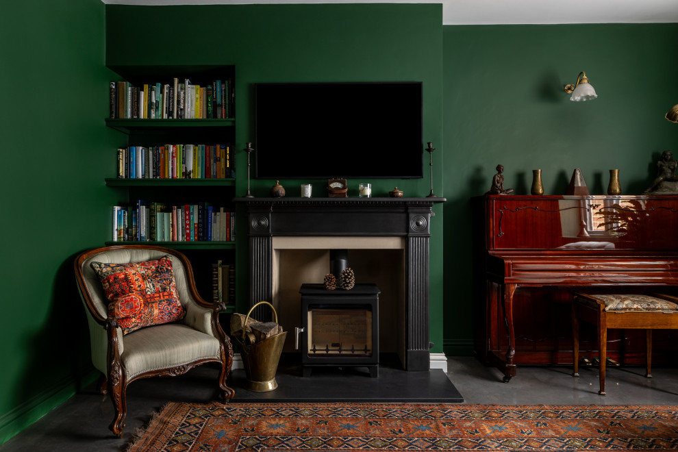 Design ideas for a traditional living room in Oxfordshire with green walls, concrete flooring, a wood burning stove, a wall mounted tv and grey floors.