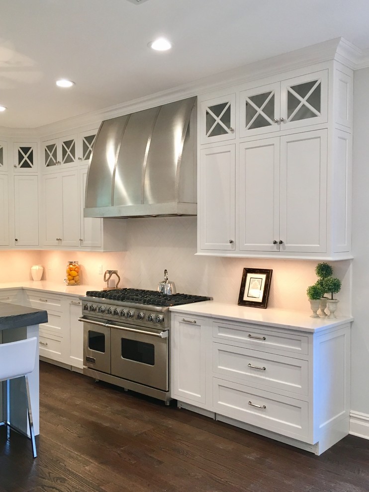 Inspiration for a mid-sized transitional u-shaped dark wood floor and brown floor kitchen remodel in New York with shaker cabinets, white cabinets, quartz countertops, white backsplash, stainless steel appliances and an island