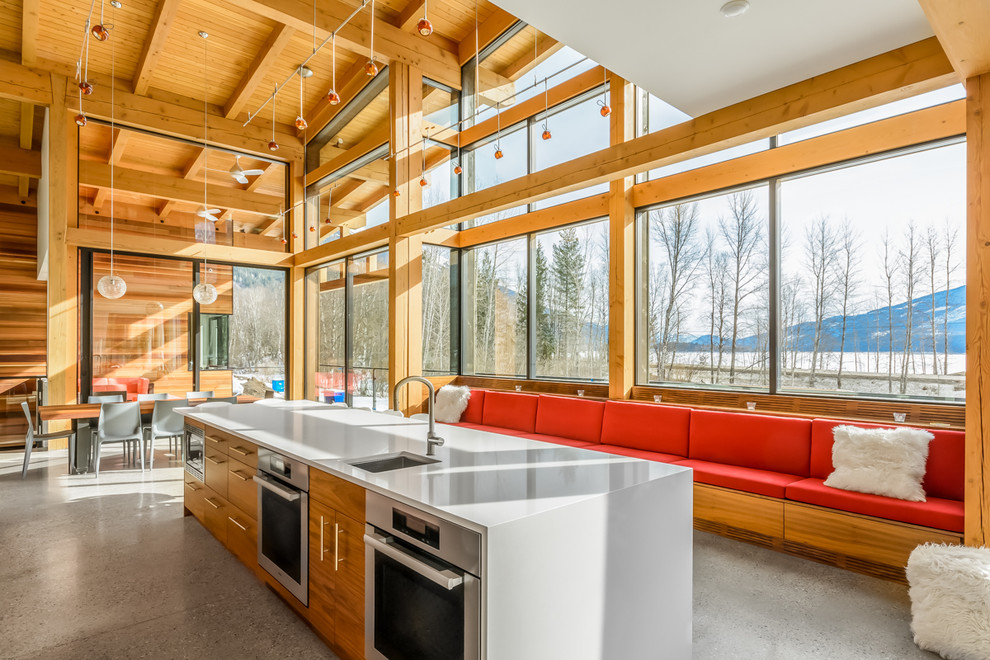 Example of a mountain style galley concrete floor open concept kitchen design in Vancouver with an undermount sink, flat-panel cabinets, medium tone wood cabinets, stainless steel appliances and an island