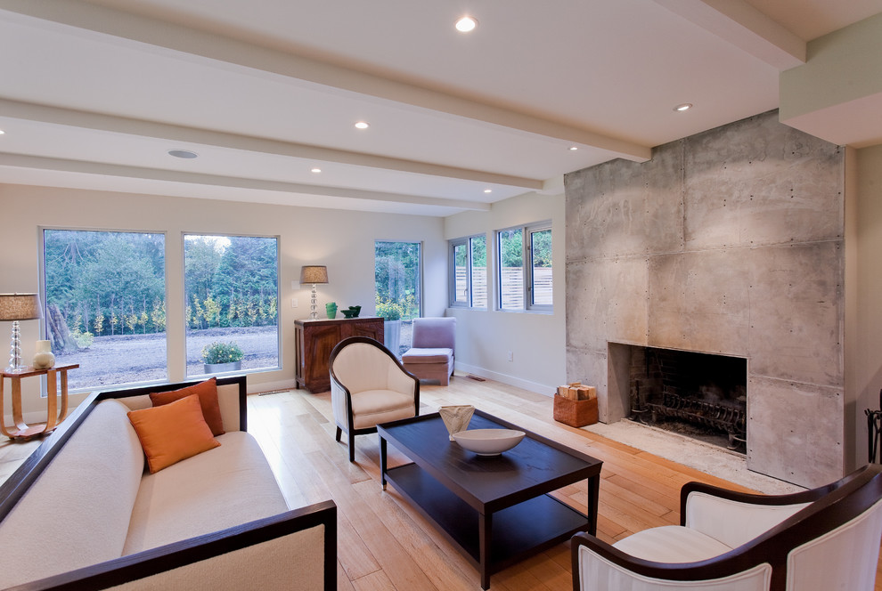 Inspiration for a large contemporary formal open concept living room in Vancouver with a standard fireplace, a concrete fireplace surround, beige walls, light hardwood floors, no tv and brown floor.