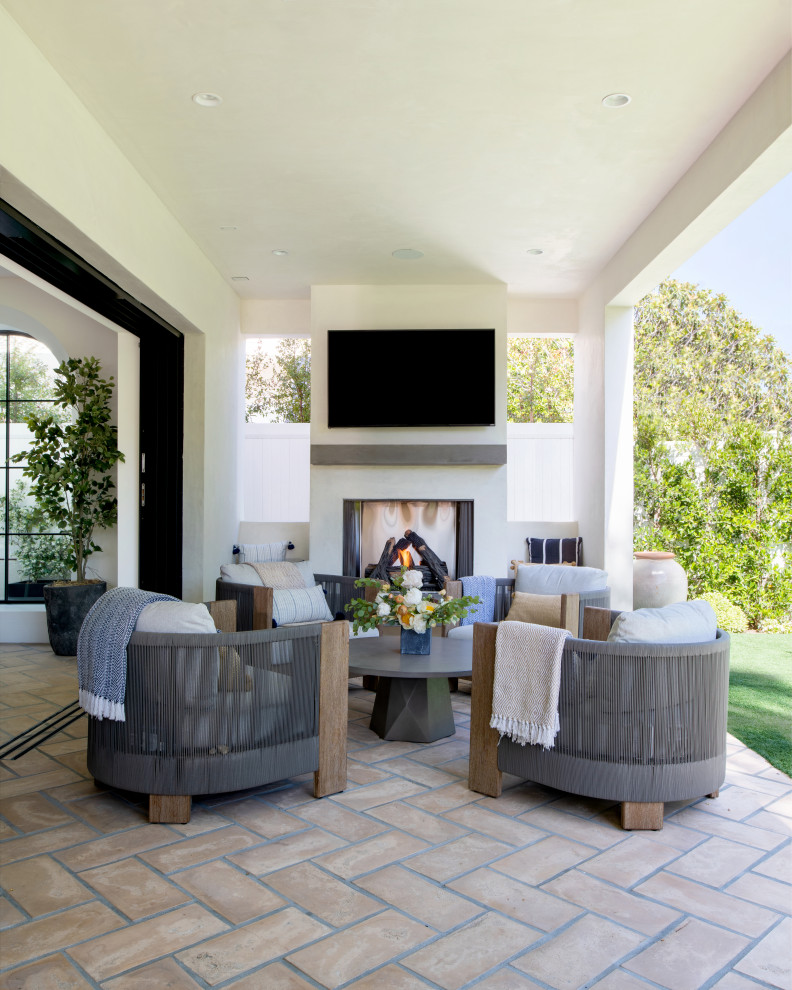 Design ideas for a large mediterranean backyard verandah in Los Angeles with with fireplace, tile and a roof extension.
