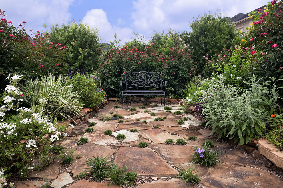 Eclectic backyard garden in Houston with natural stone pavers for summer.