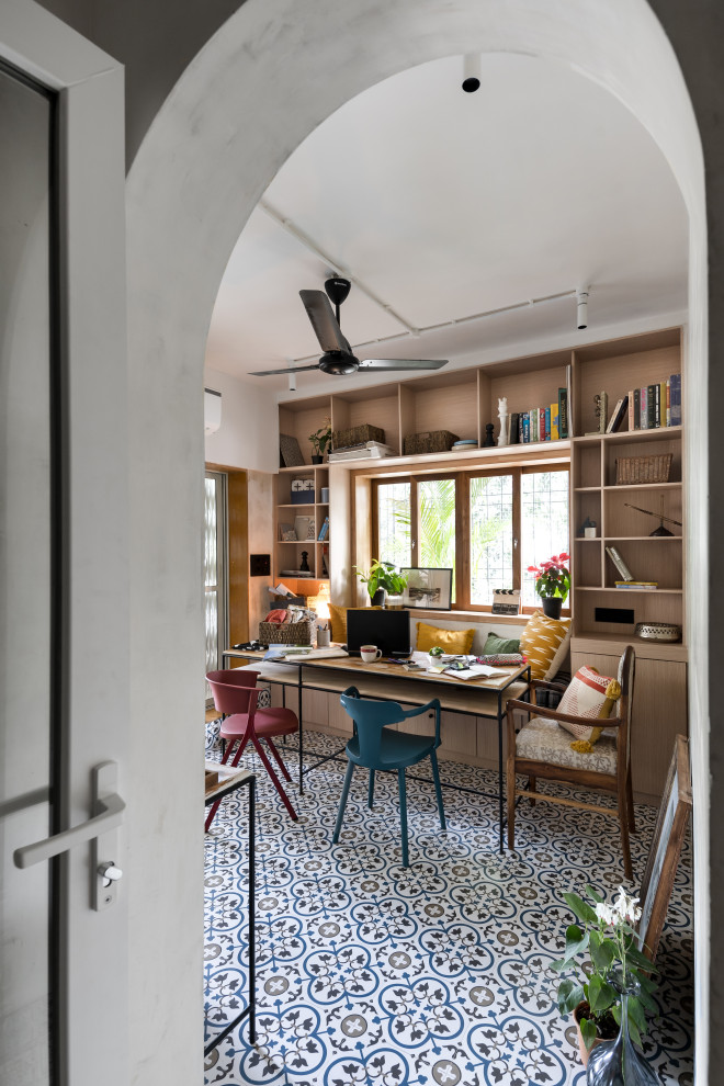 Inspiration for an eclectic home office in Mumbai with white walls, a built-in desk and multi-coloured floors.