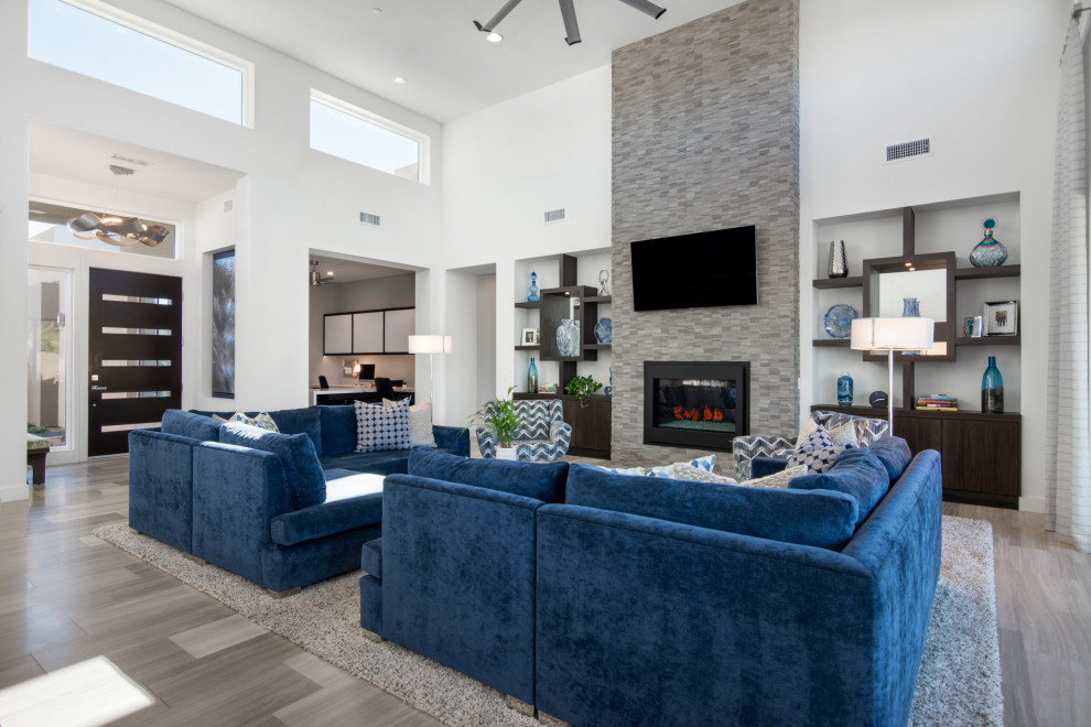 Inspiration for an expansive contemporary open concept living room in Los Angeles with white walls, limestone floors, a standard fireplace, a wall-mounted tv and grey floor.