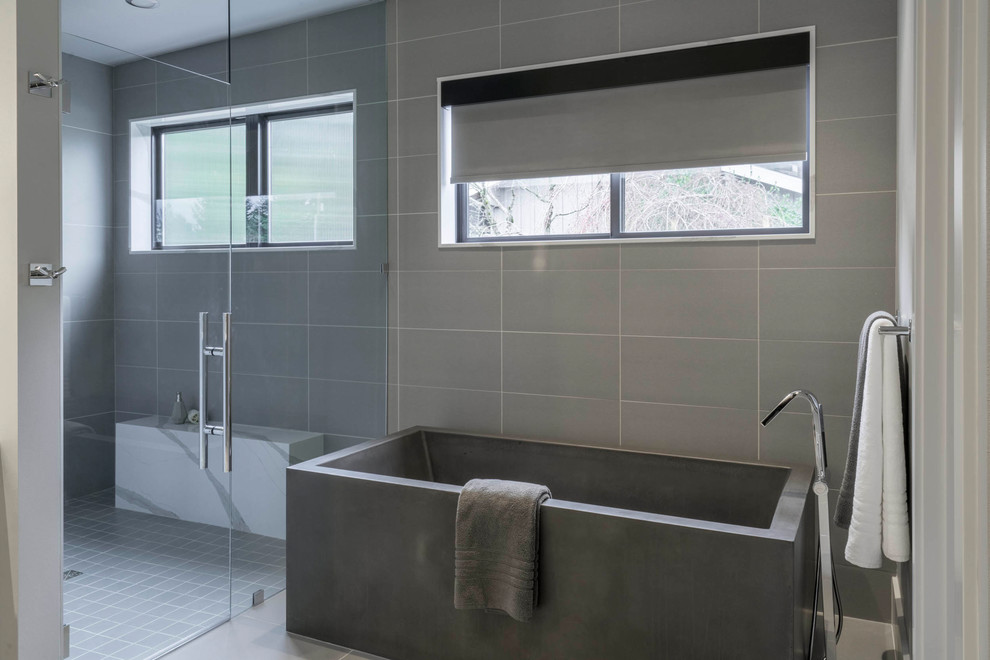 Large modern master bathroom in Seattle with a freestanding tub, a curbless shower, gray tile, porcelain tile, concrete floors and a hinged shower door.