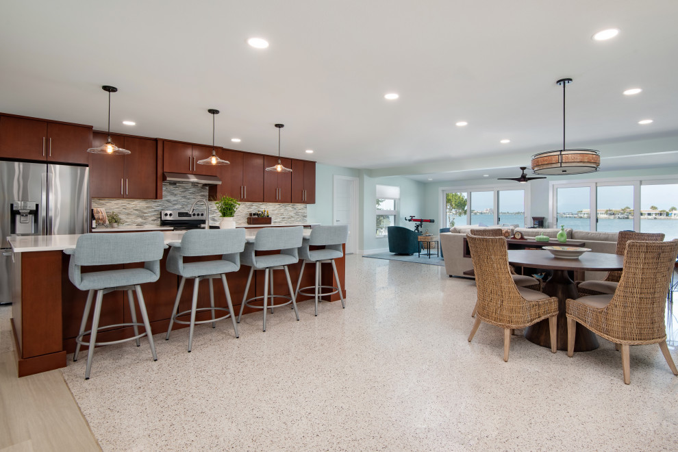 Inspiration for a mid-sized midcentury galley open plan kitchen in Tampa with flat-panel cabinets, dark wood cabinets, quartz benchtops, grey splashback, glass sheet splashback, stainless steel appliances, terrazzo floors, with island and white benchtop.