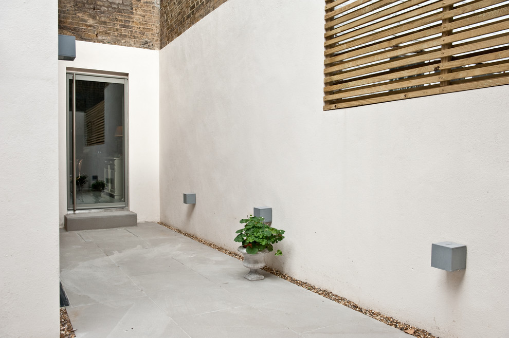 Inspiration for a mid-sized contemporary backyard patio in London with concrete pavers and no cover.