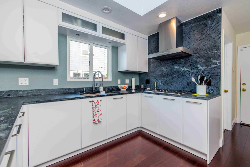 This is an example of a mid-sized contemporary u-shaped kitchen pantry with an undermount sink, flat-panel cabinets, white cabinets, solid surface benchtops, black splashback, engineered quartz splashback, stainless steel appliances, dark hardwood floors, a peninsula, brown floor, black benchtop and recessed.