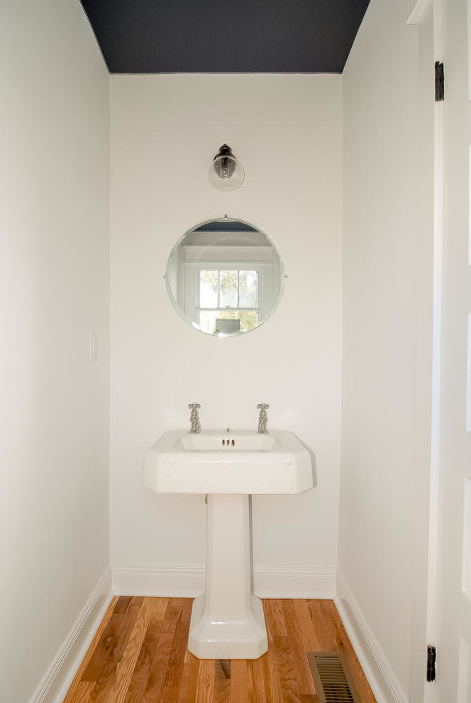 Mid-sized traditional bathroom in Nashville with a two-piece toilet, blue walls, light hardwood floors and a pedestal sink.
