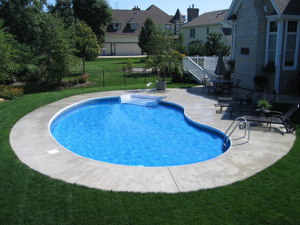 This is an example of a mid-sized traditional backyard kidney-shaped pool in Chicago with concrete slab.
