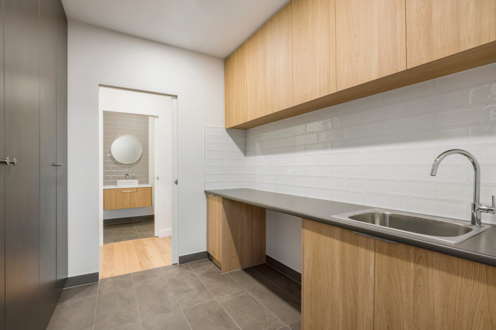 Design ideas for a large contemporary galley laundry room in Melbourne with a drop-in sink, flat-panel cabinets, laminate benchtops, white walls, ceramic floors, a side-by-side washer and dryer, grey floor and grey benchtop.